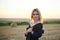 Young blond woman, wearing black jacket and jeans shorts, posing on wheat field on summer evening. Creative stylish three-quarter