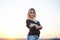 Young blond woman, wearing black jacket and jeans shorts, posing on wheat field on summer evening. Creative stylish three-quarter