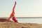 Young blond woman, wearing red leggings, doing evening exercises outside in summer. Fitness yoga stretching training outside.