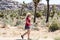 Young blonde adult woman hikes near a forest of Joshua Trees