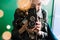 Young blonde asian female holding vintage film camera with fairy lights and bokeh around