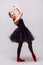 Young blonde ballerina girl dance and posing in black tutu and ballet shoes on grey background