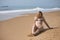 Young, blonde, beautiful woman, wearing a leopard print bikini, sitting on the shore of the beach, relaxed, lonely and calm.