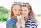 Young blonde best friends girls eating ice cream in summer hot weather in sunglasses have fun and good mood looking in camera