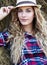 Young blonde blue-eyed country girl in hat near haystacks