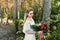 Young blonde bride with a rustic bouquet is posing outdoor in the park. Artwork. Autumn wedding ceremony outdoors.