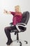 Young blonde businesswoman doing stretching, while sitting in chair