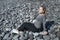 Young blonde Caucasian female sitting in a relaxing, meditating position with eyes closed, wearing a neutral outfit on the beach