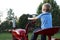 Young blonde child pretending to drive an old red tractor to the