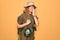 Young blonde explorer woman with blue eyes hiking wearing backpack and water canteen looking stressed and nervous with hands on