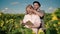 young blonde female in sunflower field reads book, guy in hat closes girl\'s eyes