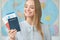 Young blonde female traveler in a tour agency holding passports close-up