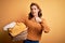 Young blonde girl doing housework chores holding laundry wicker basket happy with big smile doing ok sign, thumb up with fingers,