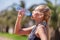 Young blonde girl drinking water during morning jogging