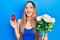 Young blonde girl holding bouquet of flowers and engagement ring smiling and laughing hard out loud because funny crazy joke