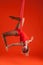 A young blonde girl with long hair in a red suit performs gymnastic and exercises on silk.