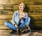 Young blonde girl with short hair in a denim jacket and jeans sits and looks