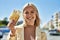 Young blonde girl smiling happy holding norway krone banknotes at the city