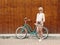 Young blonde girl is standing near the vintage green bicycle with brown vintage Cameras in orange sunglasses., warm, tonning