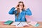 Young blonde girl studying sitting on the table with hand on head, headache because stress