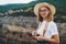 Young blonde girl in summer hat takes photo on retro camera on back ground panorama horizon mountain landscape rest outdoors