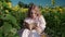 a young blonde girl in a sunflower field reads a book, looks around, waits