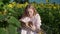 a young blonde girl in a sunflower field reads a book, looks around, waits