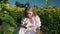 a young blonde girl in a sunflower field reads a book, looks around, waits