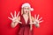 Young blonde girl wearing christmas hat afraid and terrified with fear expression stop gesture with hands, shouting in shock