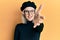 Young blonde girl wearing french look with beret smiling friendly offering handshake as greeting and welcoming