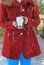 Young blonde-haired woman in red coat holding cute penguin coffee cup outside in snow