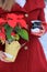 Young blonde-haired woman in red coat holding cute snowman coffee cup and Poinsettia plant