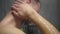 Young blonde man taking shower. Washing head with a hot water and shampoo. Close up