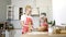 A young blonde mother with a small daughter in aprons are engaged in cooking at the table in the kitchen.