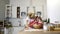 A young blonde mother with a small daughter in aprons are engaged in cooking at the table in the kitchen.