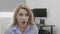 Young blonde office woman at work saying omg oh my God reaction with astonished face and opened mouth -