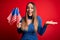 Young blonde patriotic woman holding usa flag on independence day on 4th of july very happy and excited, winner expression