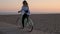 Young blonde photographer female rides bike on the beach