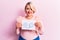 Young blonde plus size woman asking for positive change holding paper with emotion message looking positive and happy standing and