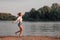 A young blonde is running freedom along the beach at dawn. A happy beautiful woman in white clothes and denim shorts on