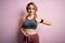 Young blonde sportswoman wearing sportswear controlling weight using tape measure on waist happy with big smile doing ok sign,