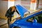 Young blonde stands near car with raised engine compartment hood