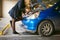 Young blonde stands near car with raised engine compartment hood