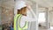 Young blonde woman architect wearing hardhat standing backwards at construction site