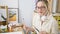 Young blonde woman artist sitting on table choosing paintbrush wearing headphones at art studio