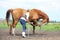 Young blonde woman asking chestnut horse to bow