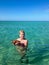 Young blonde woman bathing in a sea and holding starfish in hands