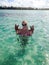 Young blonde woman bathing in a sea and holding starfish in hands