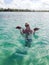 Young blonde woman bathing in a sea and holding starfish in hands