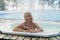 Young blonde woman in bathtub jacuzzi outdoors at winter